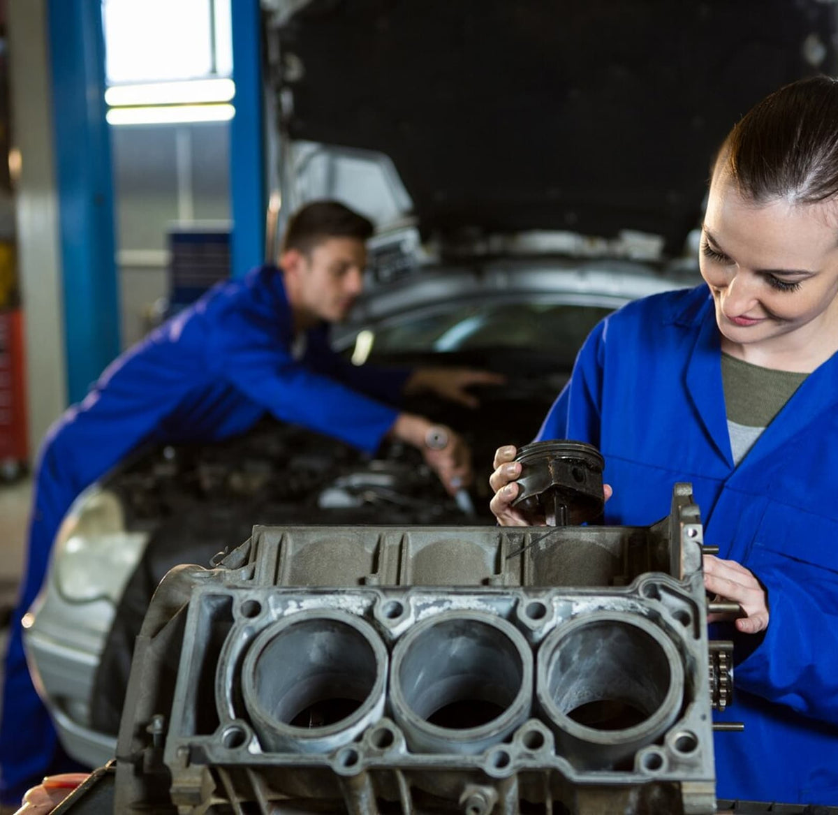 Mechanics inspecting an engine component in an automotive workshop